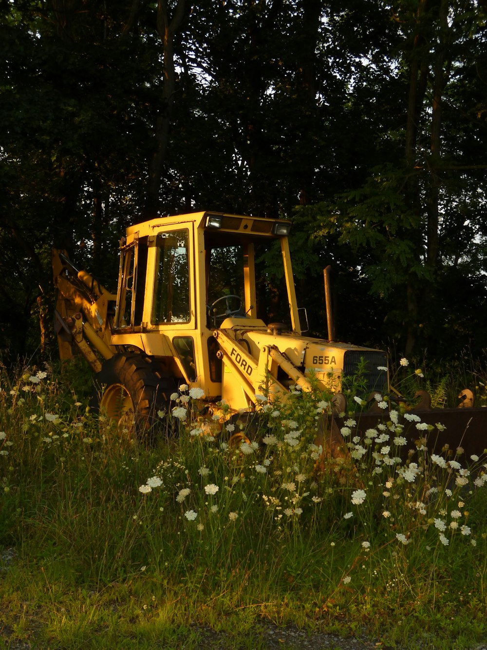 a yellow bulldozer parked in a field of flowers