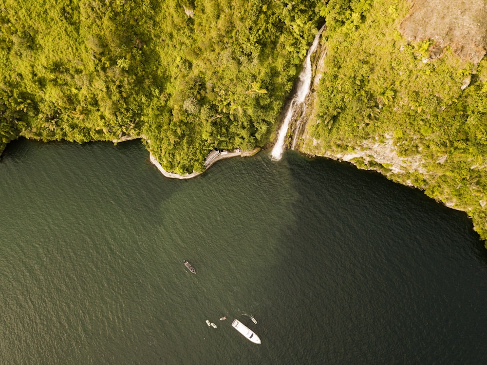 an aerial view of a boat in the water near a waterfall