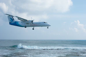 a plane flying over the ocean with a sky background