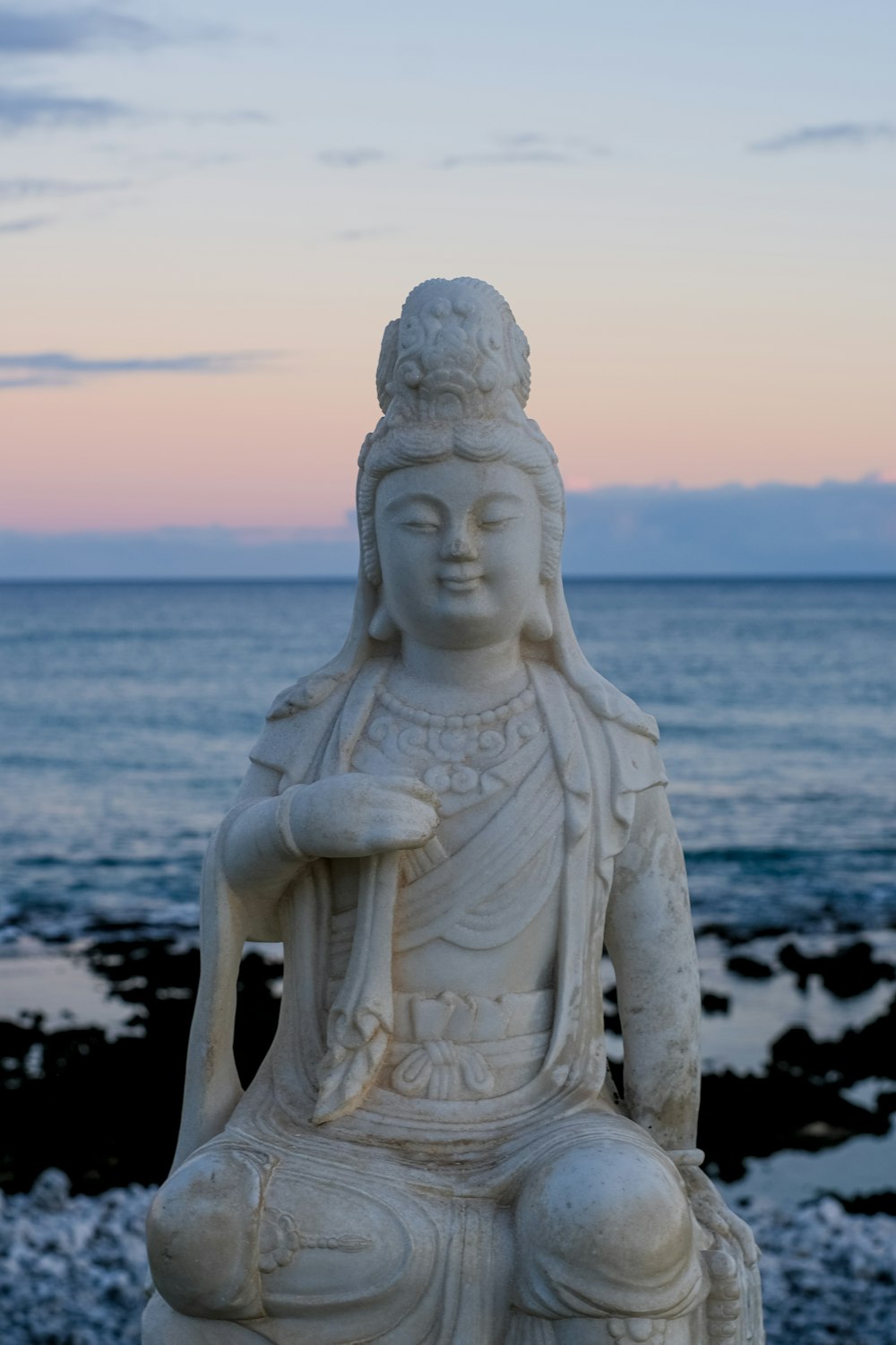 una estatua blanca sentada en la cima de una playa junto al océano