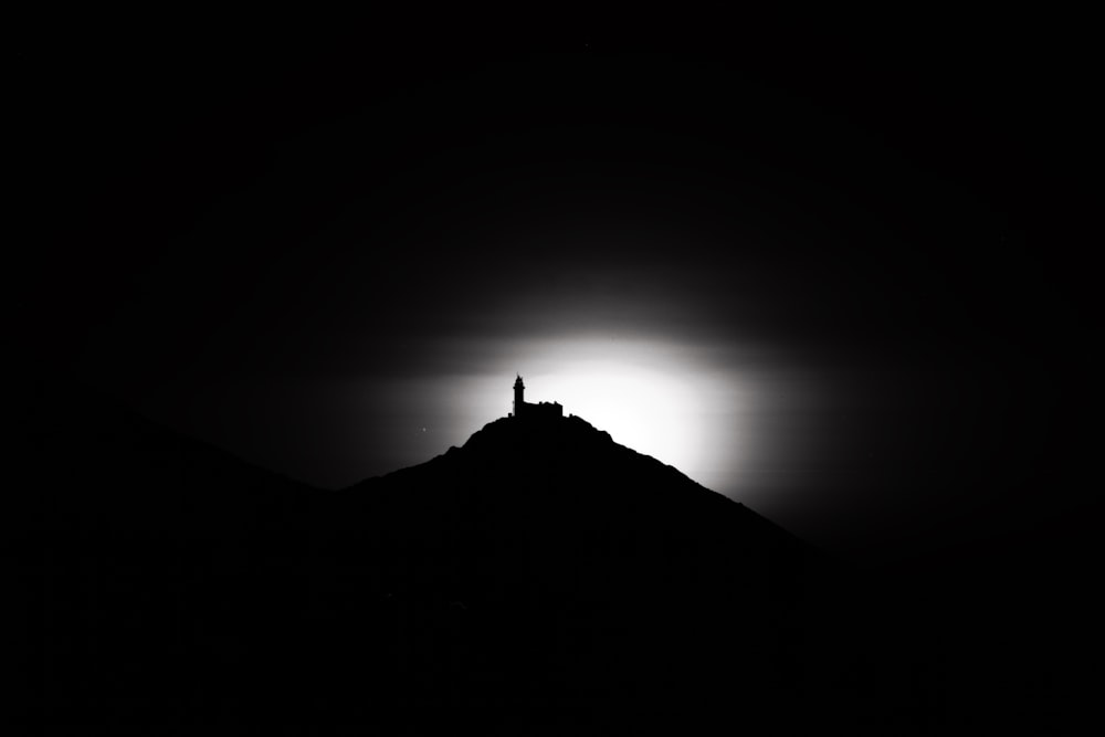 a black and white photo of the sun behind a mountain