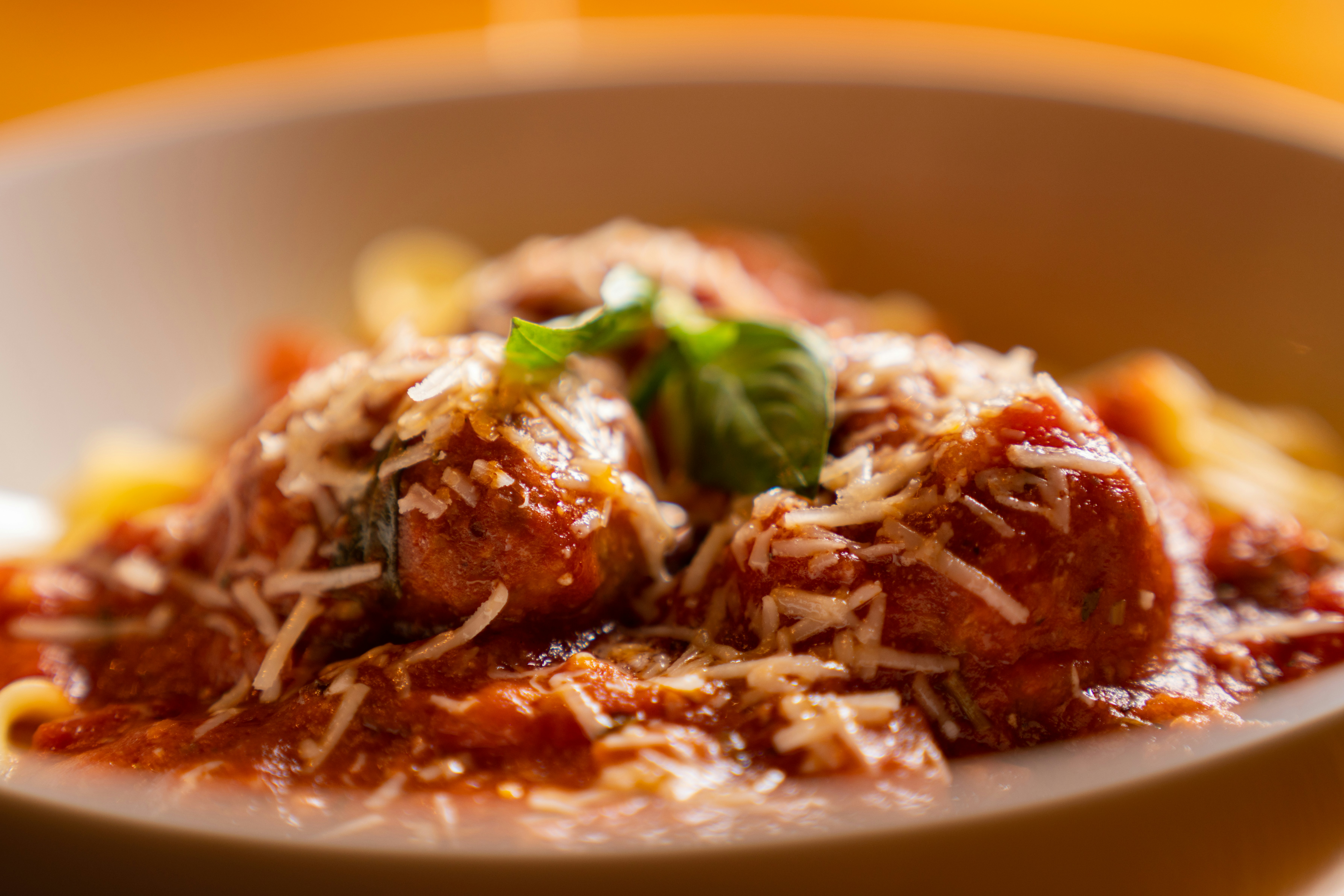 Braised meatballs in tomato sauce topped with grated parmesan in a rustic bowl