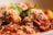 Meatballs covered in a rich tomato sauce topped with grated cheese are garnished with fresh basil. The dish appears appetizing and well-plated, with a focus on the textures of the cheese and sauce.