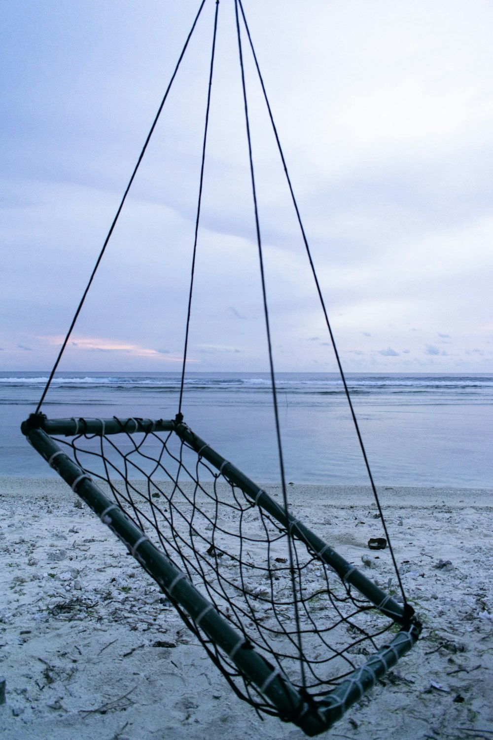 a hammock hanging from a rope on the beach
