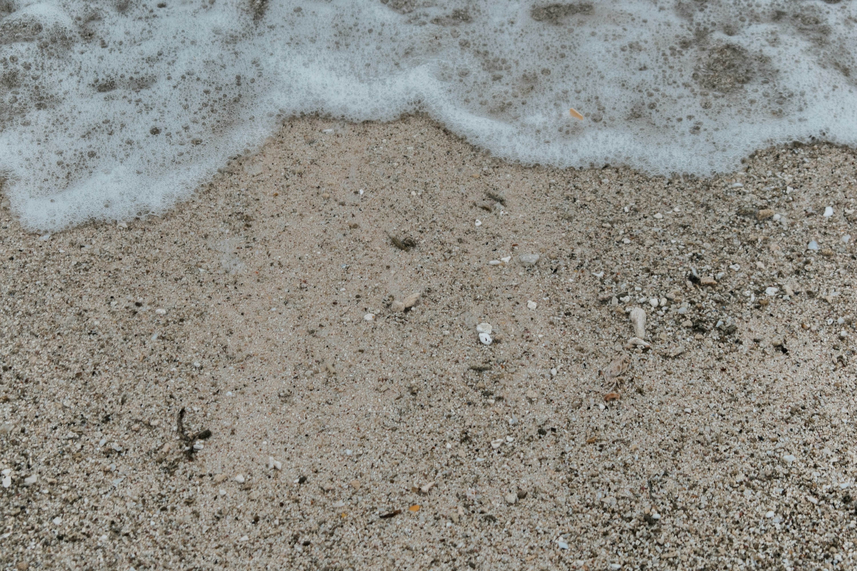 a sandy beach with a wave coming in to shore
