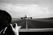 Wide shot of an airplane taxiing with the airport terminal in the background.