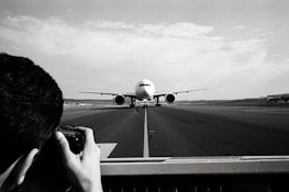 Wide shot of an airplane taxiing with the airport terminal in the background.