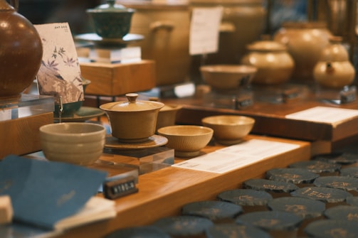 Close-up of a vendor arranging handmade pottery on a wooden table with subtle palm leaf decorations.