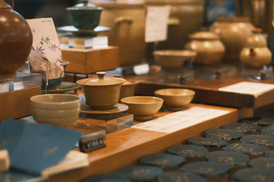 A close-up of handcrafted pottery and decorative bowls arranged on a reclaimed wood table.