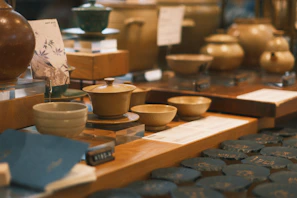 A collection of Tamgroute pottery pieces displayed on a rustic wooden table against a warm beige wall.