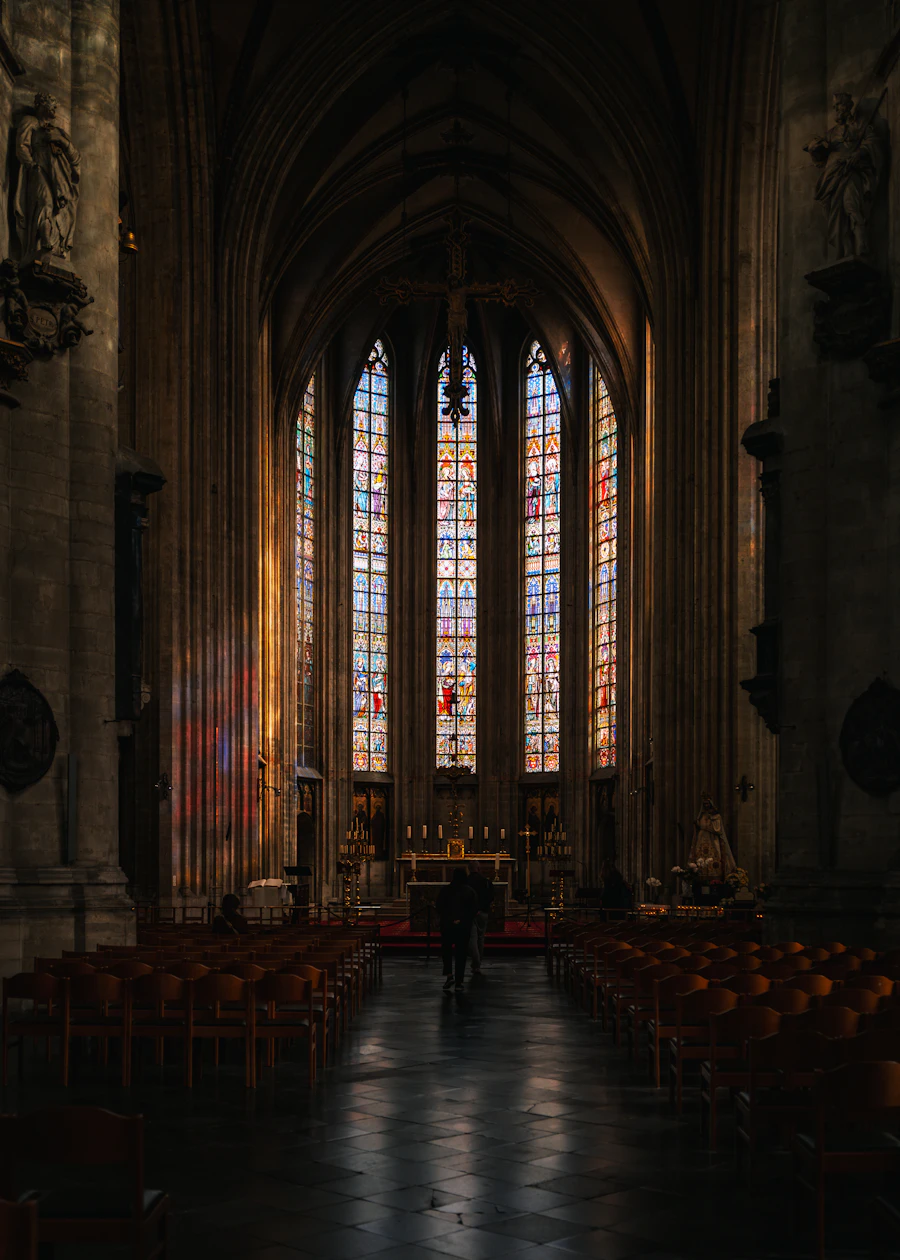 Tall stained-glass windows glowing inside a dim cathedral