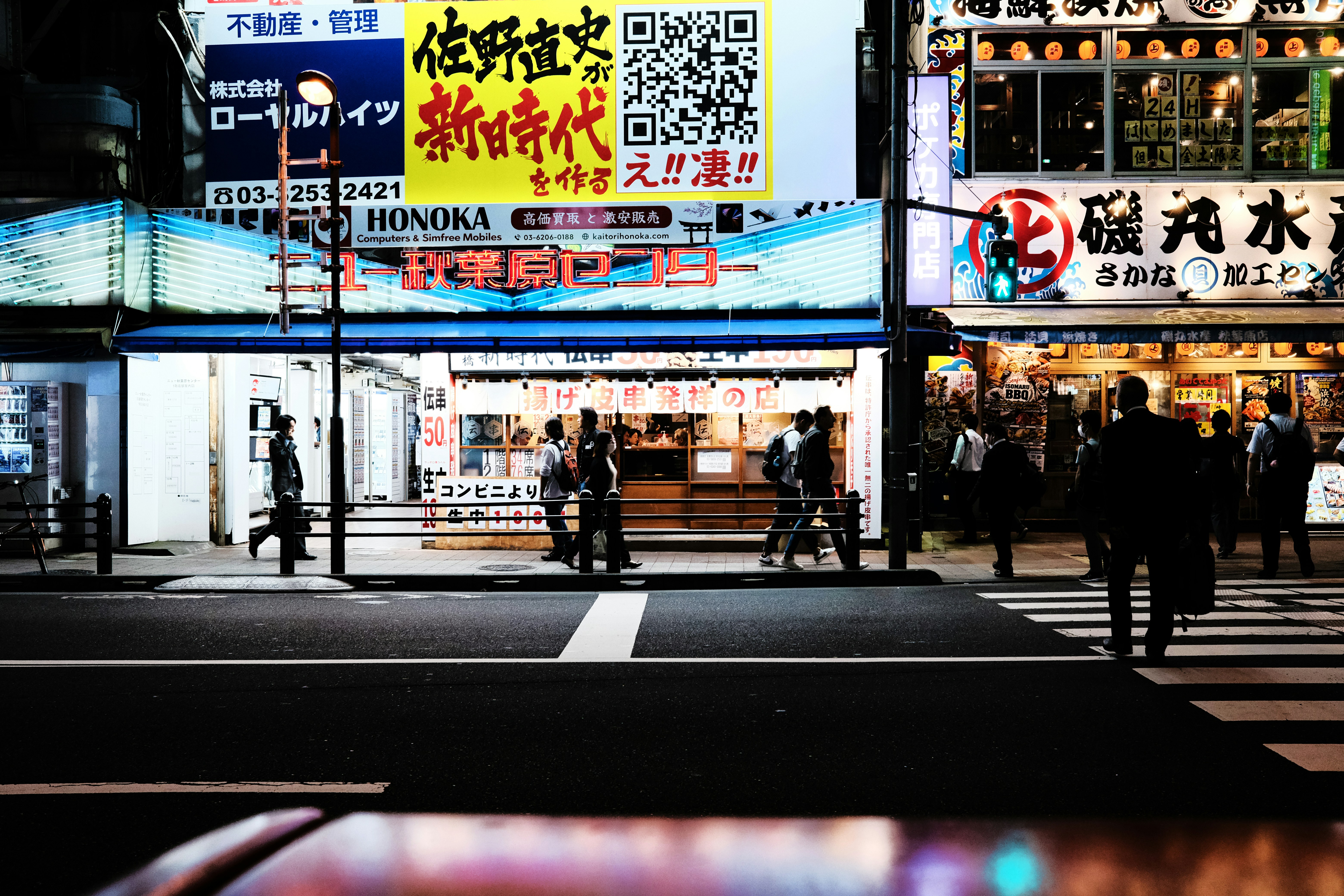 a group of people walking across a street at night