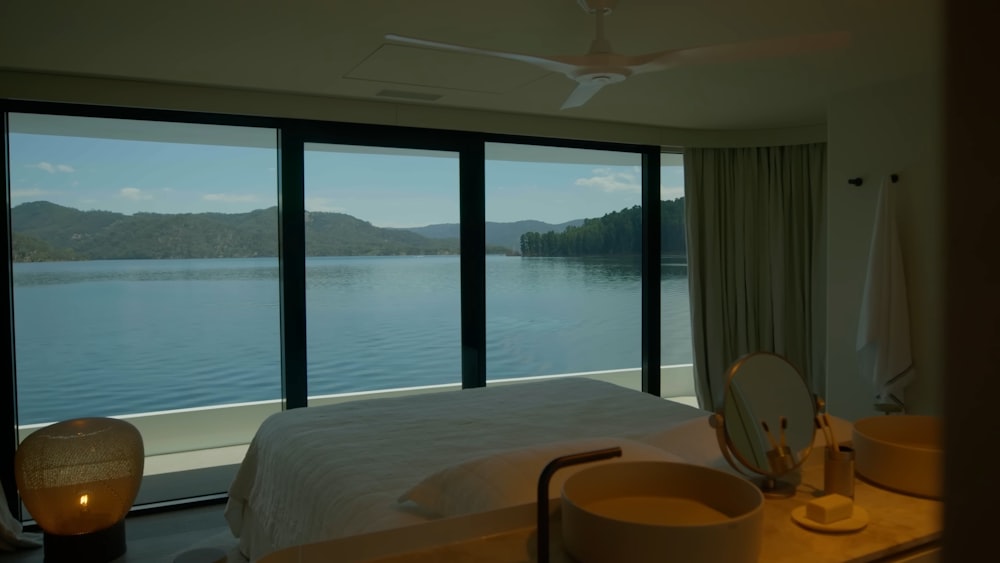 a bedroom with a large window overlooking a body of water