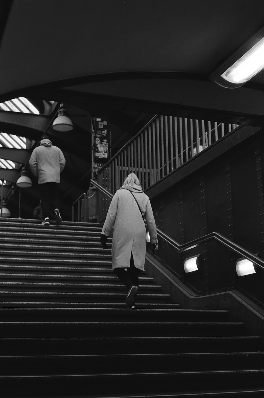 a black and white photo of a woman walking down a set of stairs