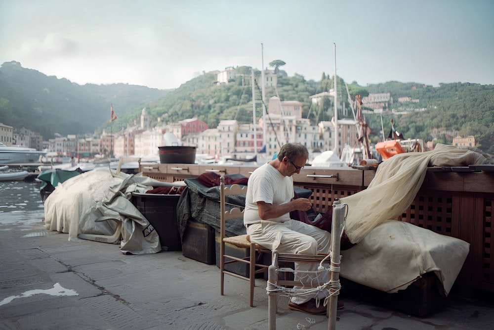 a man sitting on a chair next to a body of water