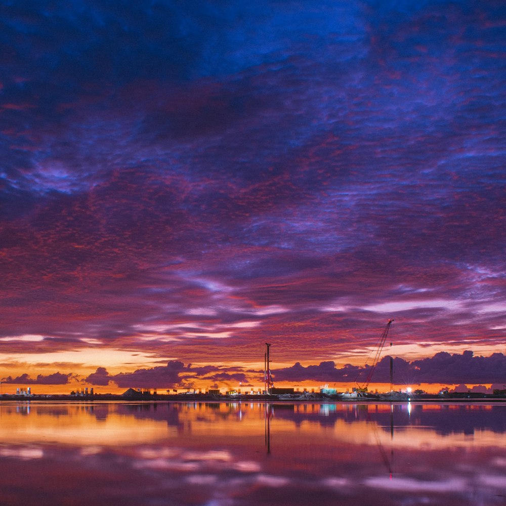 a purple and blue sky with clouds reflecting in the water