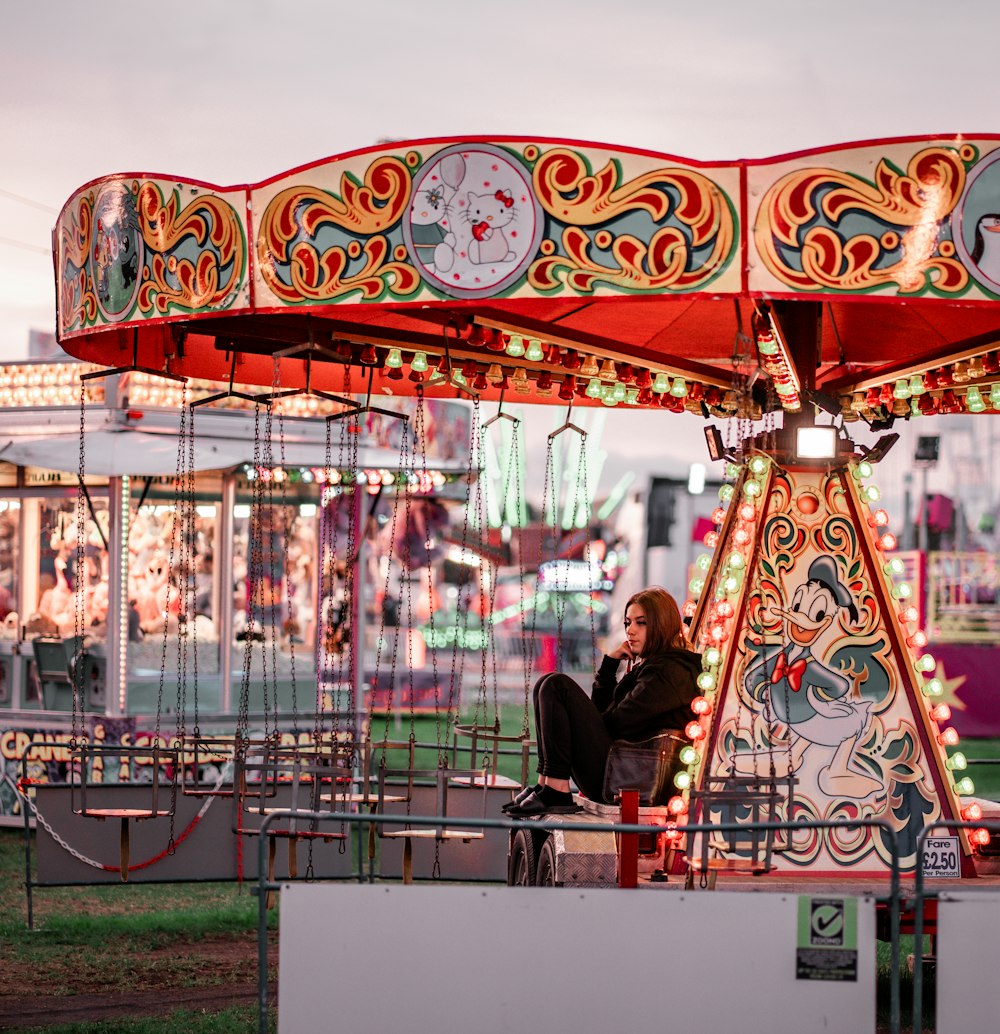 a woman sitting on a merry go round at a carnival