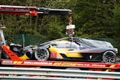 a car being lifted onto a truck by a crane