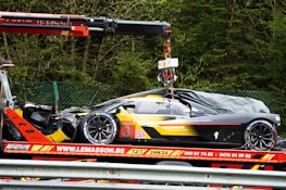 a car being lifted onto a truck by a crane