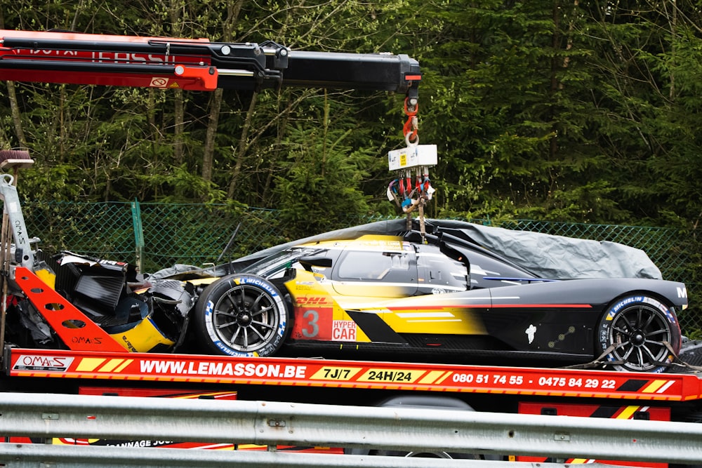 a car being lifted onto a truck by a crane