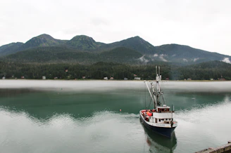 A serene morning on a misty lake with a lone angler casting a line from a wooden boat.