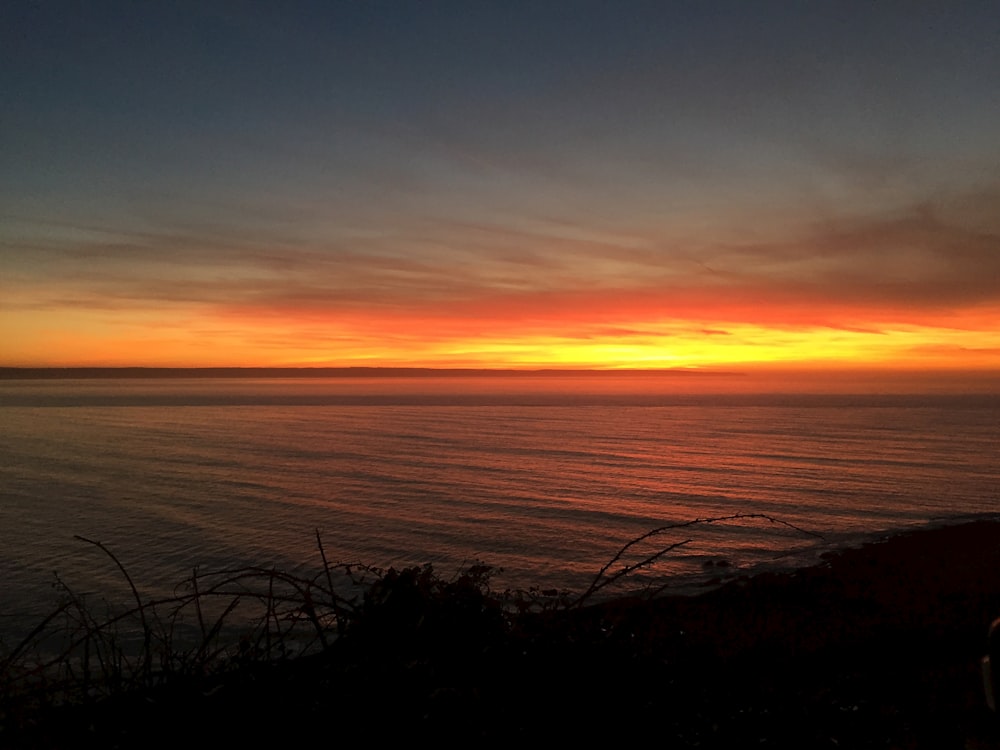 the sun is setting over the ocean and the water