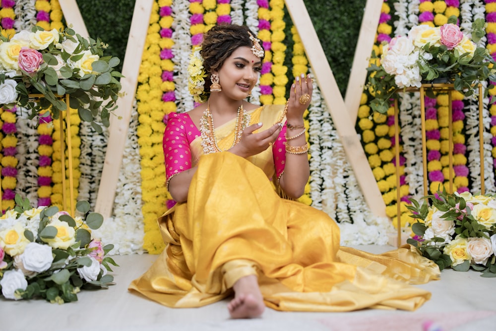 a woman sitting on the ground in front of flowers