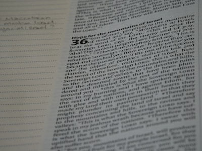 A page from a book with text that appears to be from the Bible. The text is partially in focus and discusses a prophecy to the mountains of Israel. Notes are handwritten in the margin on the left side of the page.