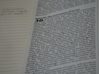 A page from a book with text that appears to be from the Bible. The text is partially in focus and discusses a prophecy to the mountains of Israel. Notes are handwritten in the margin on the left side of the page.