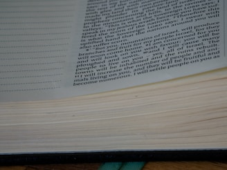 A close-up view of an open book showing text on the right page, with visible lines and spaces on the left page, suggesting note-taking sections. The text is in English and appears to be centered vertically as if captured at a slight angle, revealing the thickness of the pages.