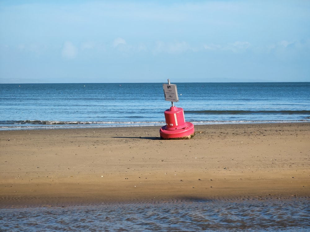 a red fire hydrant sitting on top of a sandy beach