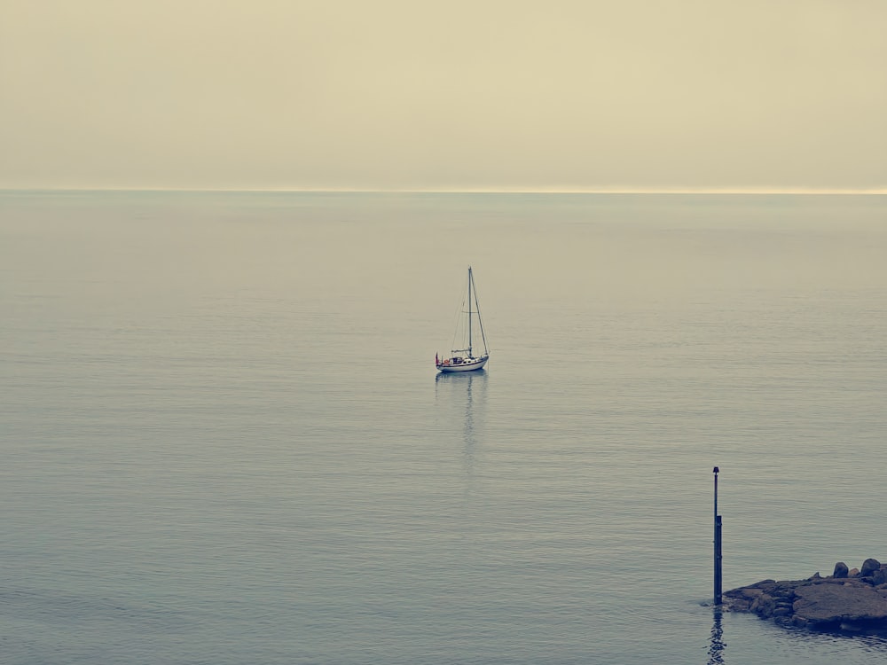 a sailboat in the middle of the ocean on a foggy day