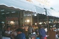 A bustling market street in Southeast Asia filled with colorful fabrics and smiling vendors.