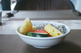 a white bowl filled with fruit on top of a table