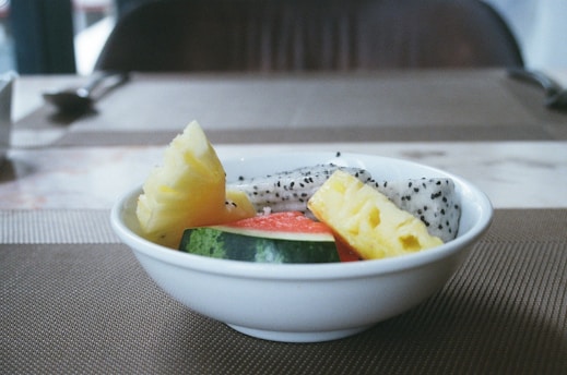 a white bowl filled with fruit on top of a table