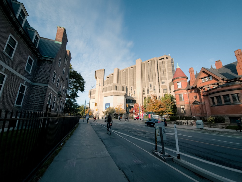 a person riding a bike down a street next to tall buildings