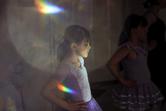 Children in colorful ballet outfits practicing graceful poses in a bright studio.
