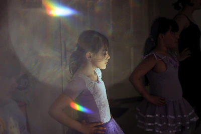 Children in colorful ballet outfits practicing graceful poses in a bright studio.
