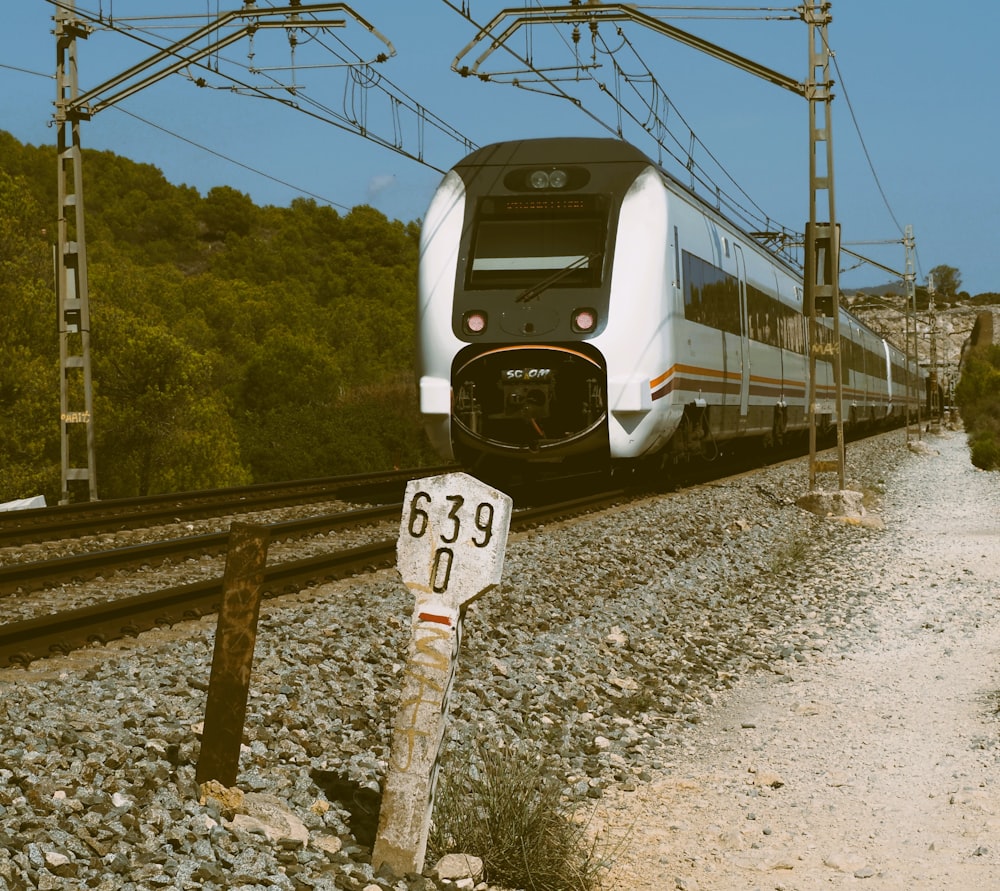 a train traveling down tracks next to a forest