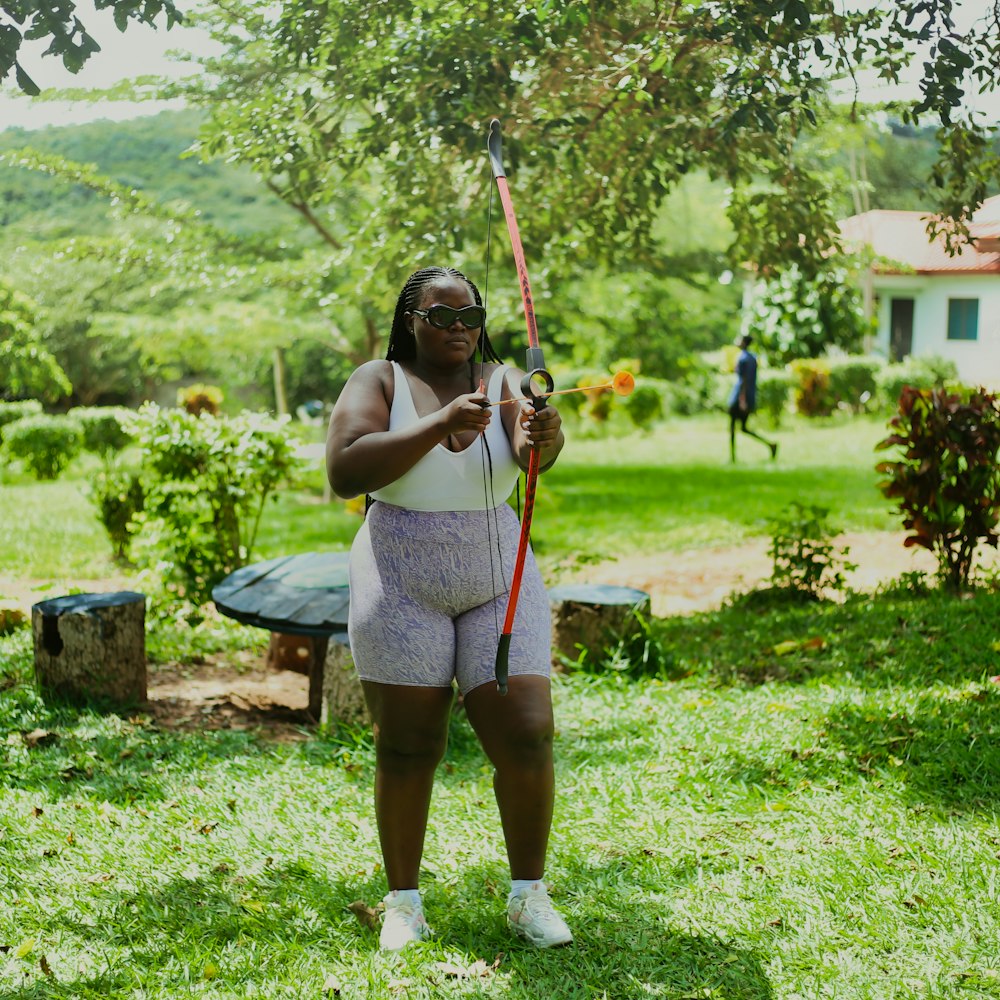 a woman holding a bow and arrow in a yard