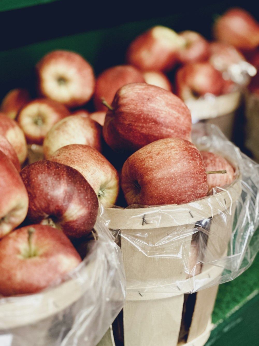 Un manojo de manzanas están en canastas sobre una mesa