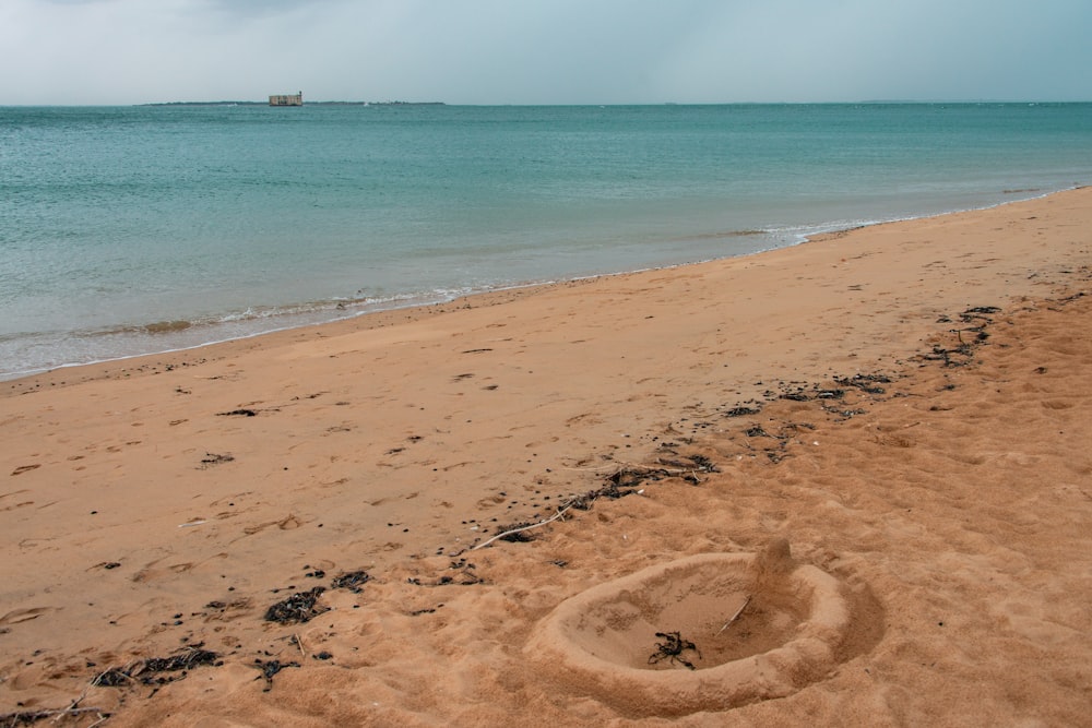 a sandy beach next to the ocean under a cloudy sky