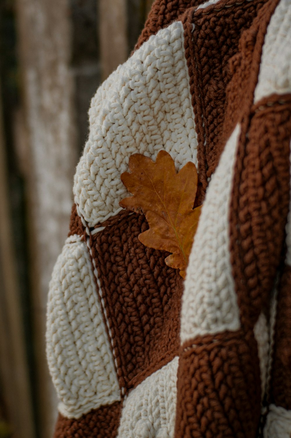 a brown and white crocheted blanket with a leaf on it