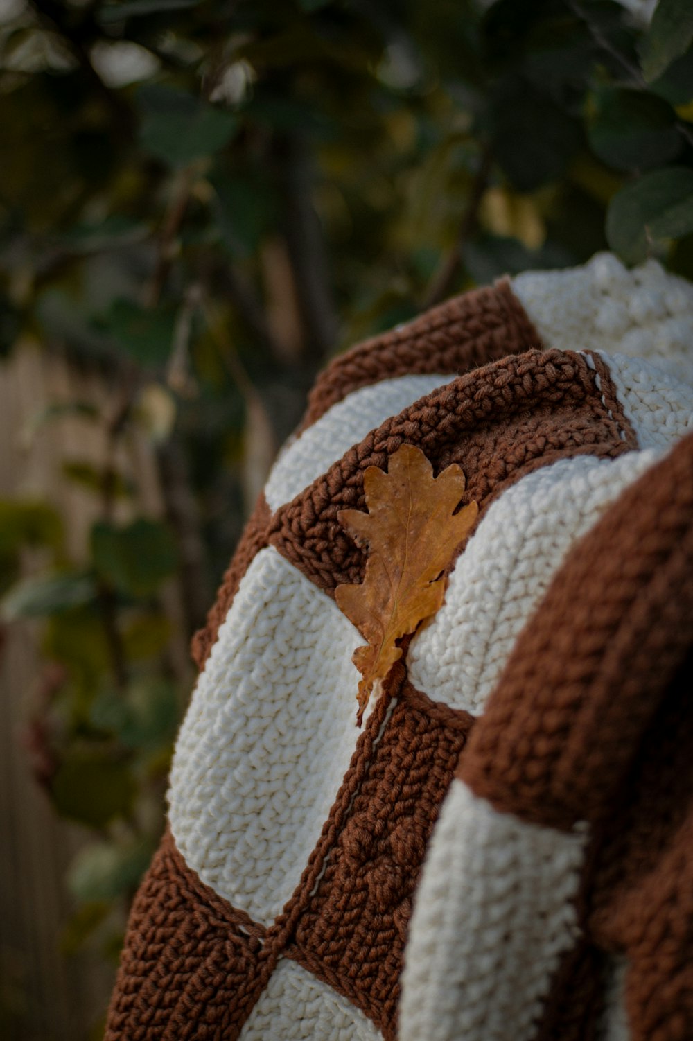 a brown and white sweater with a leaf on it