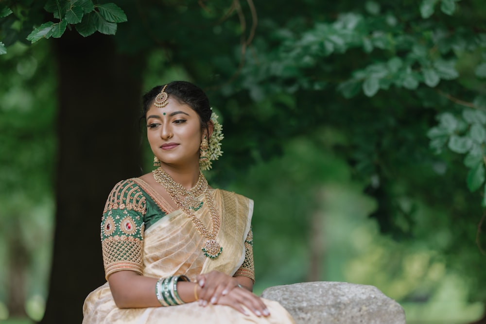 a woman in a sari sitting on a rock