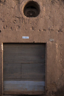 A close-up photo of a technician repairing a rolling shutter in a dimly lit urban setting.
