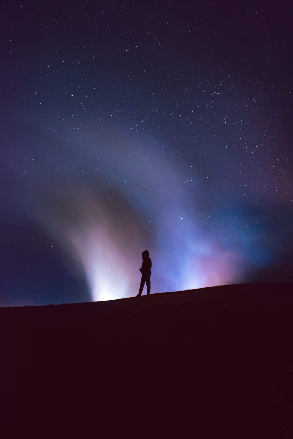 a person standing on top of a hill under a night sky