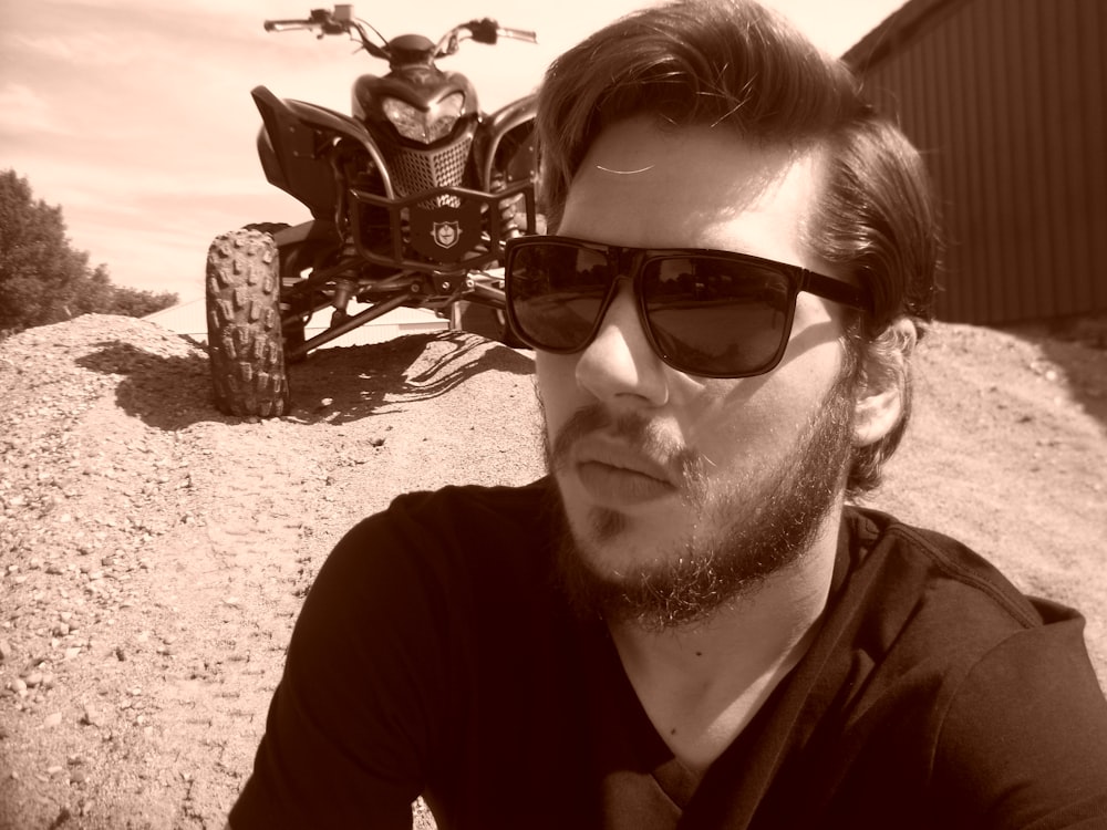 a man wearing sunglasses sitting in front of a motorcycle
