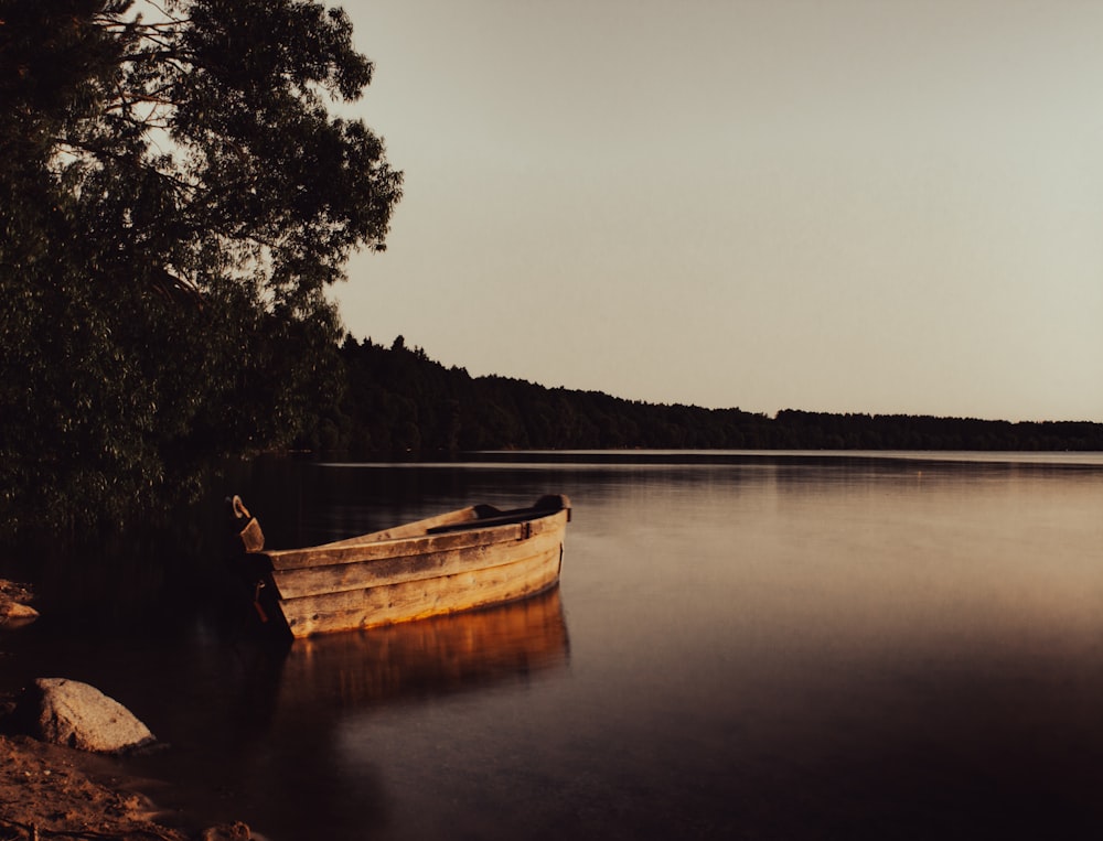 um barco sentado no topo de um lago ao lado de uma floresta