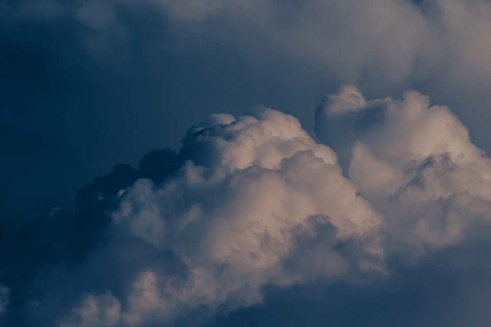 a plane flying through a cloudy blue sky